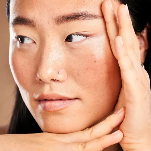 Closeup face, hand frame and asian woman in studio with skincare, skin glow or healthy cosmetics. H.